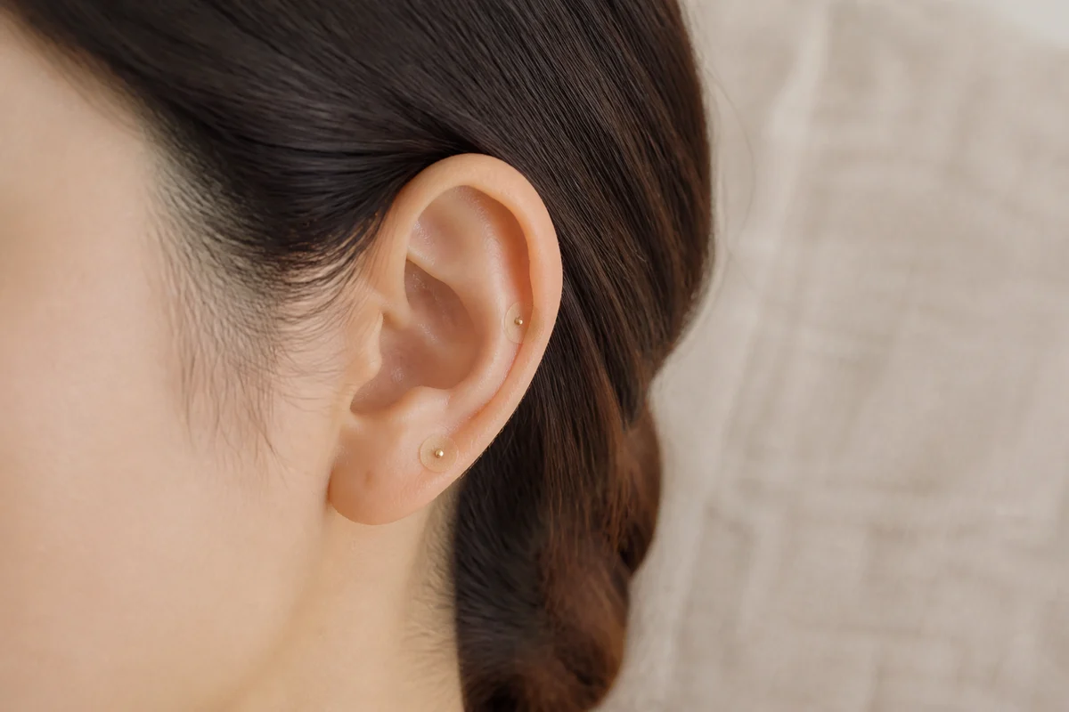 小さな耳つぼシールを貼った耳のイメージ