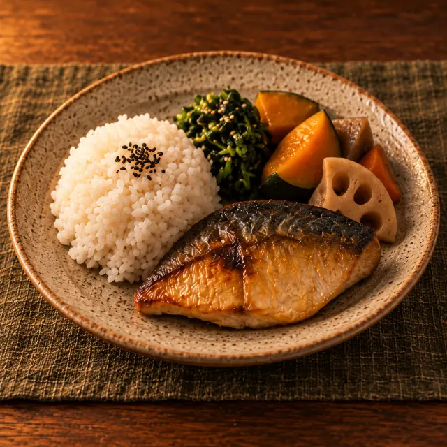 木の卓上で、米飯と焼き魚、野菜を一皿に盛り付けた食事のイメージ